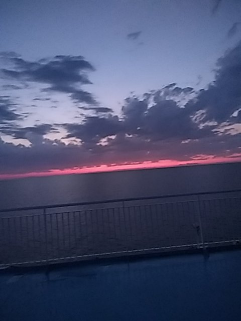 Le soir, au large, le ciel rougeoie après le coucher du soleil