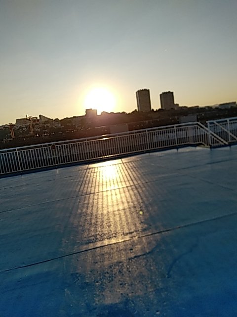 Le soleil se lève derrière les immeubles de la ville, vu du pont