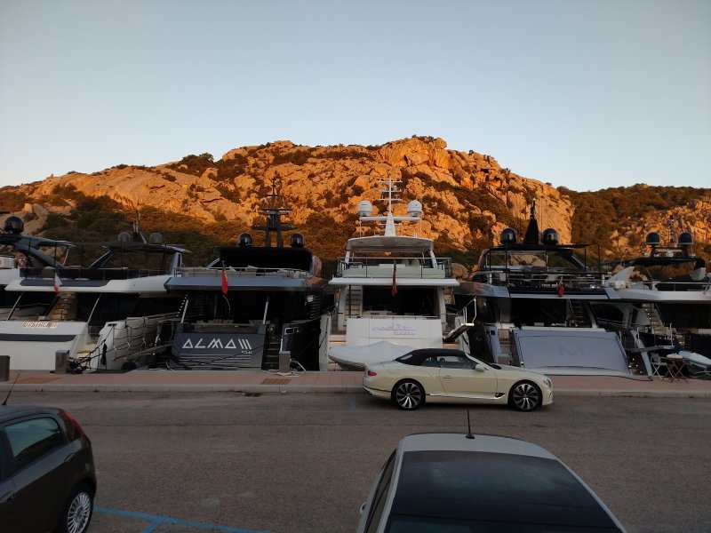 Au petit matin, des yachts à quai au pied d'une montagne éclairée par le soleil levant