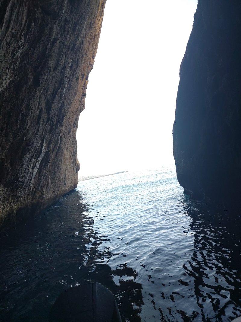 Vue de l'intérieur de la grotte : l'entrée, une fente de lumière sur la mer