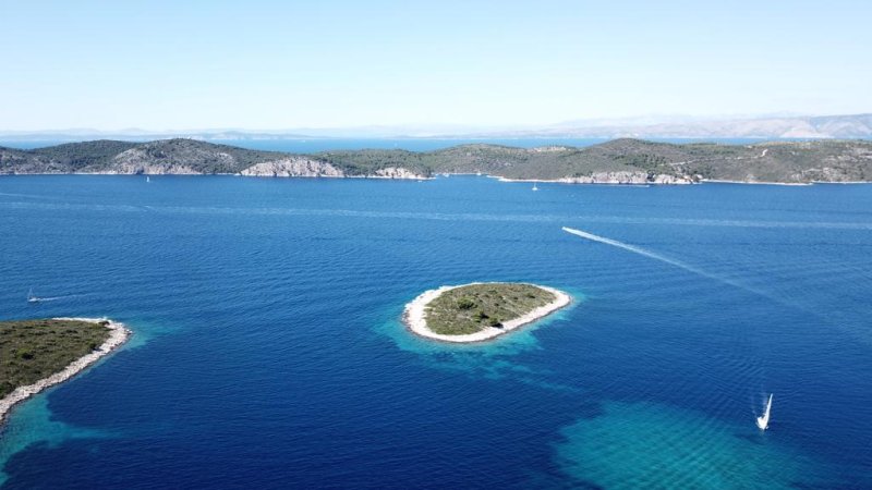 Un îlot cerné d'eau turquoise, vu du drone