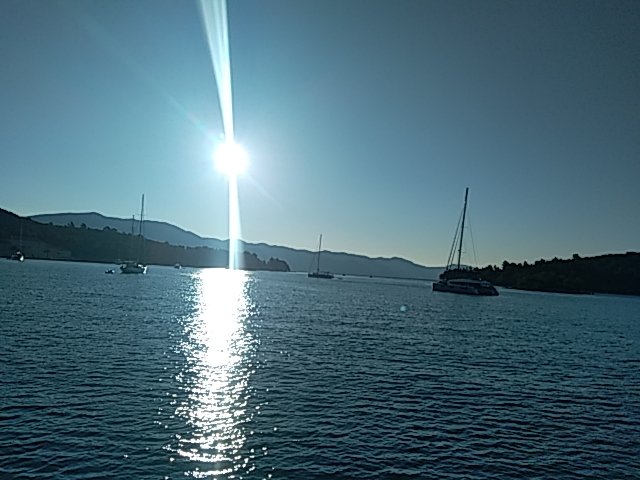 Au petit matin, le soleil sur l'eau entre les voiliers au mouillage
